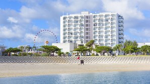 A beachfront hotel with a Ferris wheel in the background, a sandy beach, and a clear sky. - Condominium Hotel Monpa (Chatan)
