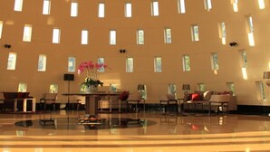 A spacious lobby with a modern design, featuring a large central table, seating areas, and a ceiling with unique light fixtures. - D'primahotel Tangerang (Tangerang)