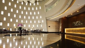 A spacious lobby with a modern design, featuring a central reception desk, multiple seating areas, and a large, open floor plan. - D'primahotel Tangerang (Tangerang)