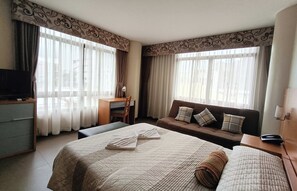 A hotel room with a large bed, a sofa, a desk, and a television. - Fuente Oro Business Suites Cebu powered by Cocotel (Cebu City)