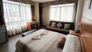 Une chambre d’hôtel avec un lit, un canapé, un bureau et une chaise.