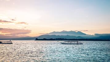 Un lago tranquilo con barcos y una cadena montañosa al fondo.