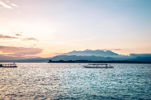 Un lago tranquilo con barcos y una cadena montañosa al fondo.