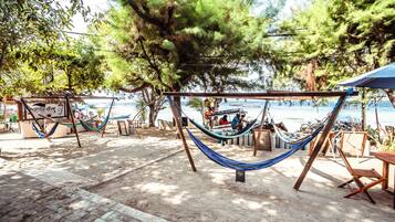 A beachside area with hammocks and a dining setup overlooking the sea.