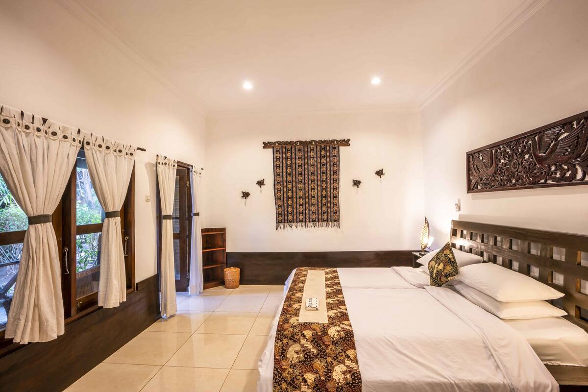 Un dormitorio con cama, cortinas, un adorno en la pared y cabecero.