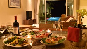 Una mesa de comedor dispuesta con platos de comida, copas de vino y una botella de vino Merlot.