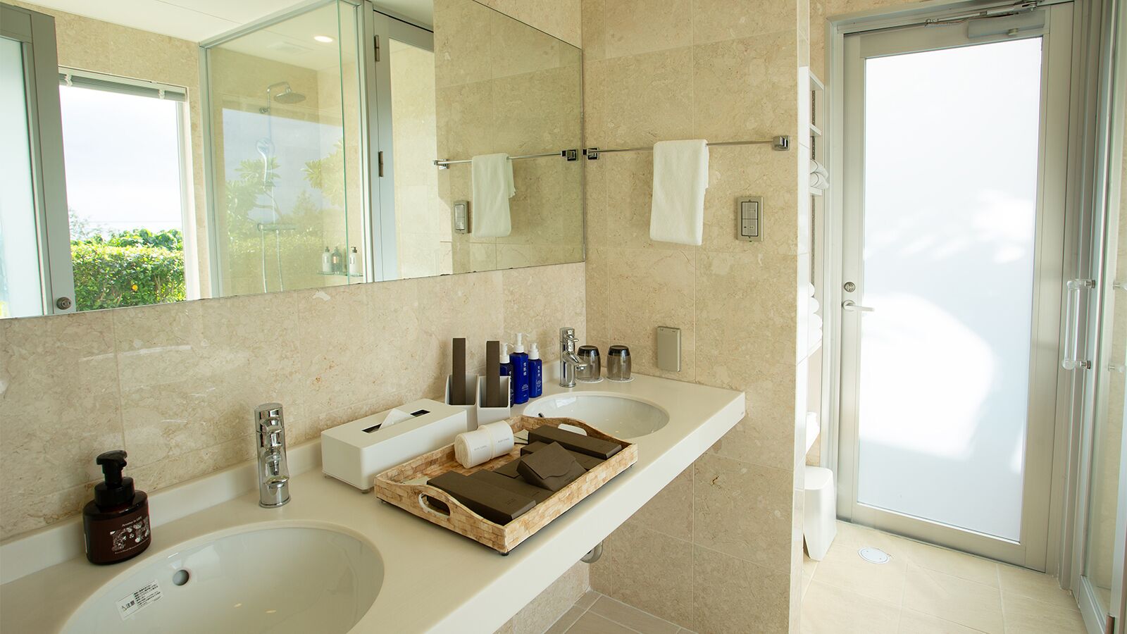 Un baño moderno con dos lavamanos, un espejo grande y una ducha con mampara de vidrio.