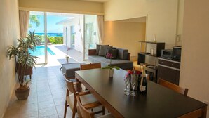 Una cocina moderna con comedor, sofá y vistas a la piscina y al océano.