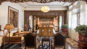 A traditional interior with wooden furniture, a patterned rug, and a decorative ceiling. - Cours Et Pavillons (Beijing)