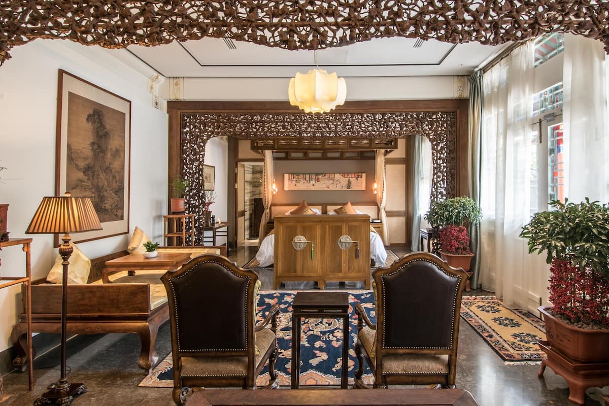 A traditional interior with wooden furniture, a patterned rug, and a decorative ceiling.