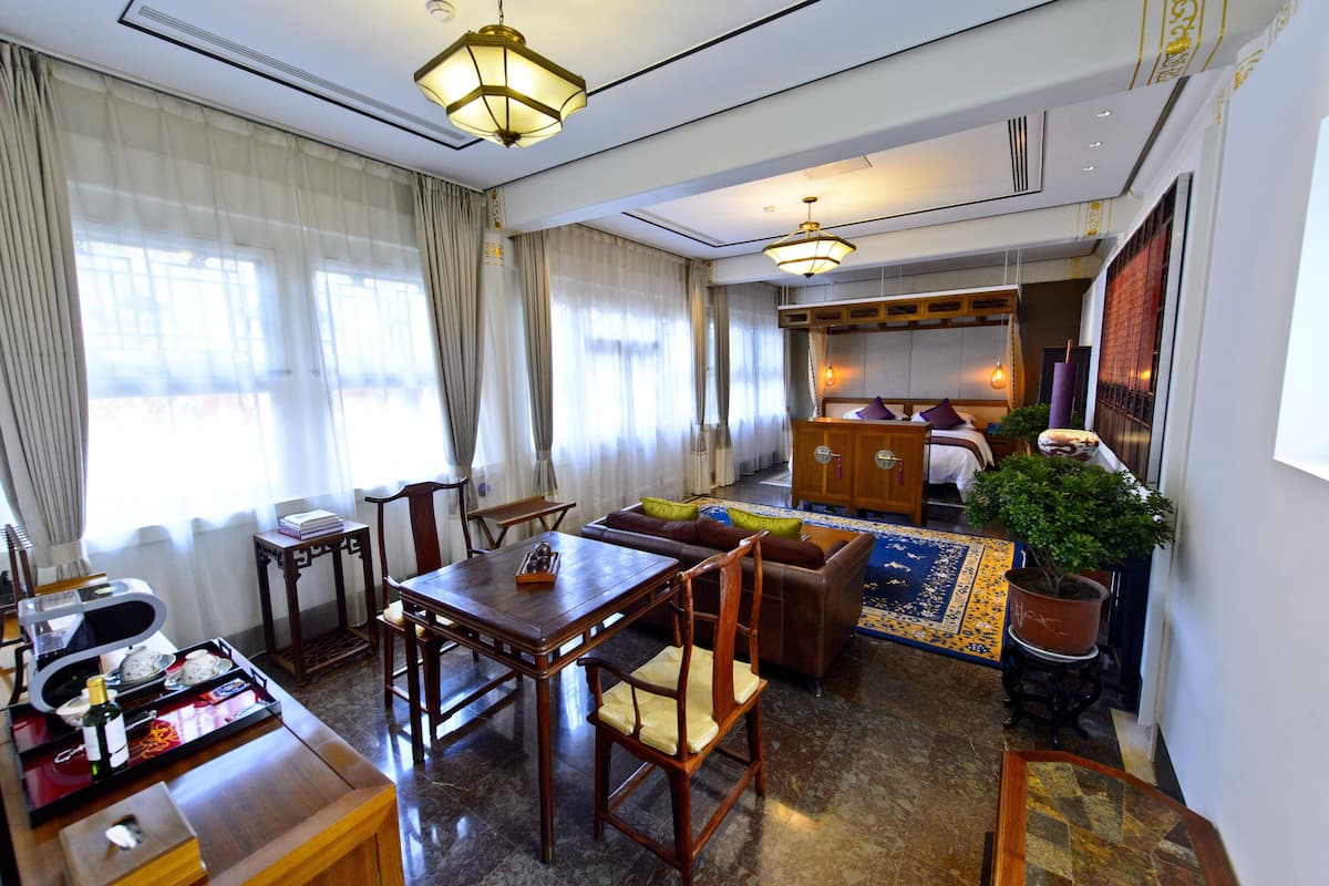 A hotel room with a dining area, a sofa, a bed, and a potted plant.