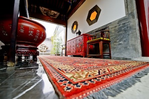 Un intérieur traditionnel avec une grande armoire rouge, un tapis à motifs et une chaise en bois.