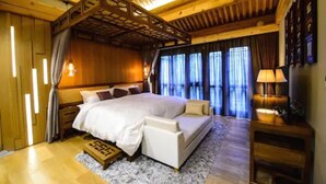 A cozy bedroom with a wooden ceiling, a large bed, a nightstand, and a lamp. - Cours Et Pavillons (Beijing)