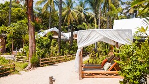 A beachside accommodation with wooden lounge chairs, a canopy, and a sandy path. - La Cocoteraie Ecolodge- Glamping (Gili Trawangan)