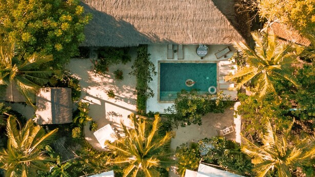 An aerial view of a resort with a pool, thatched-roof buildings, and numerous palm trees. - La Cocoteraie Ecolodge- Glamping (Gili Trawangan)