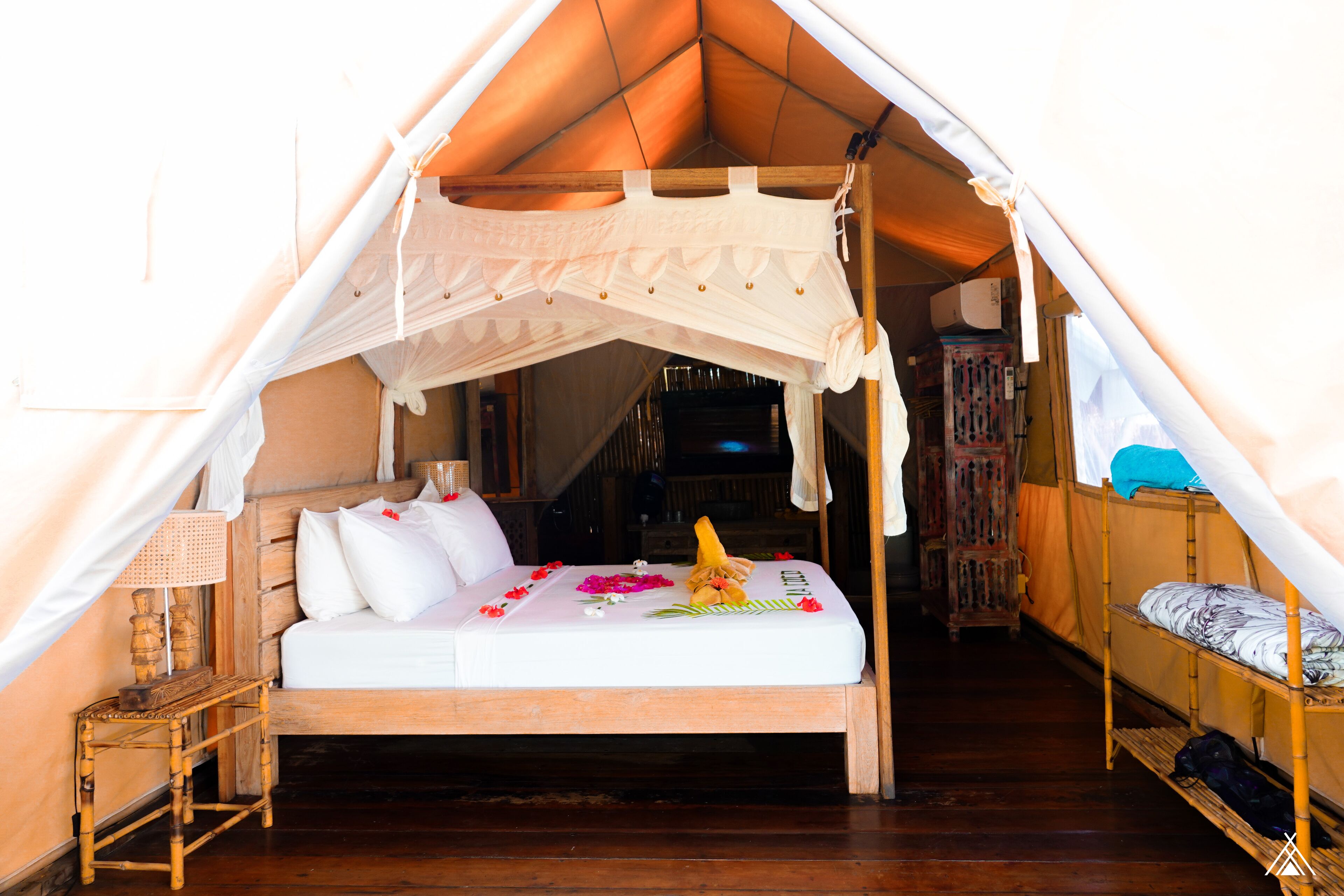 A tent with a bed, wooden furniture, and a small table.