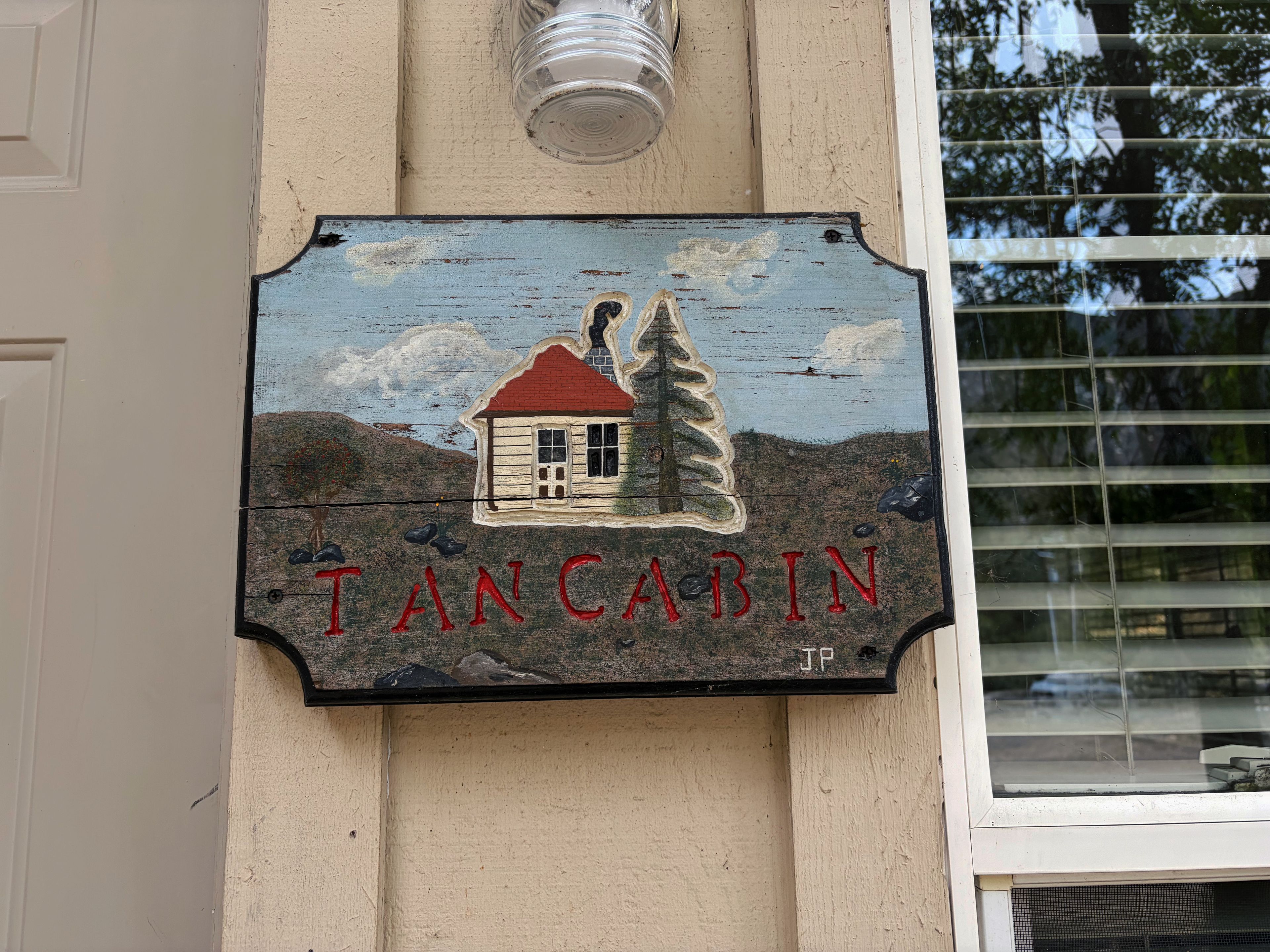 A sign with a house illustration and the name 'TANCABIN' on a building wall.
