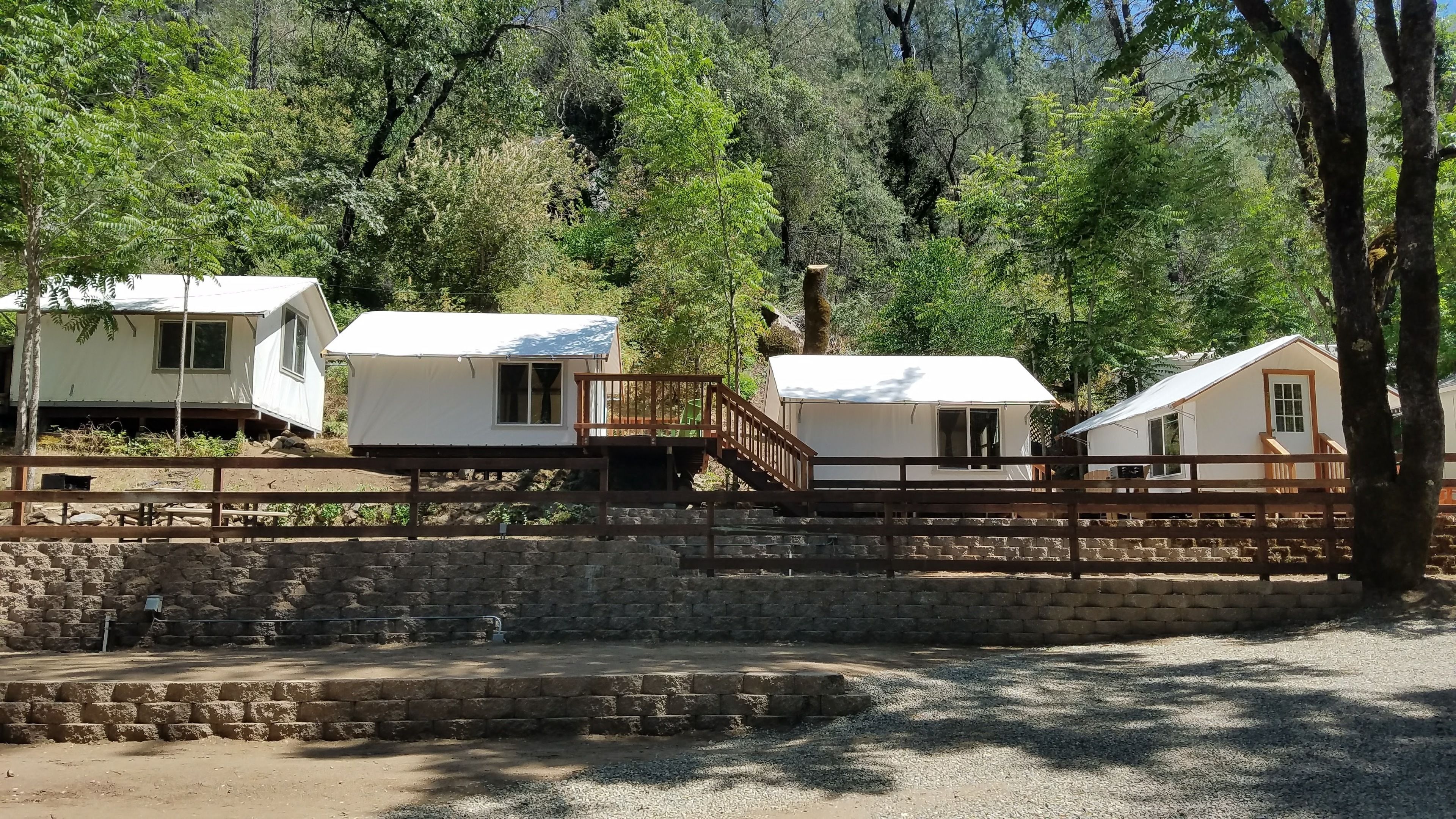 Um camping com várias cabanas brancas, cada uma com uma pequena varanda e uma janela.