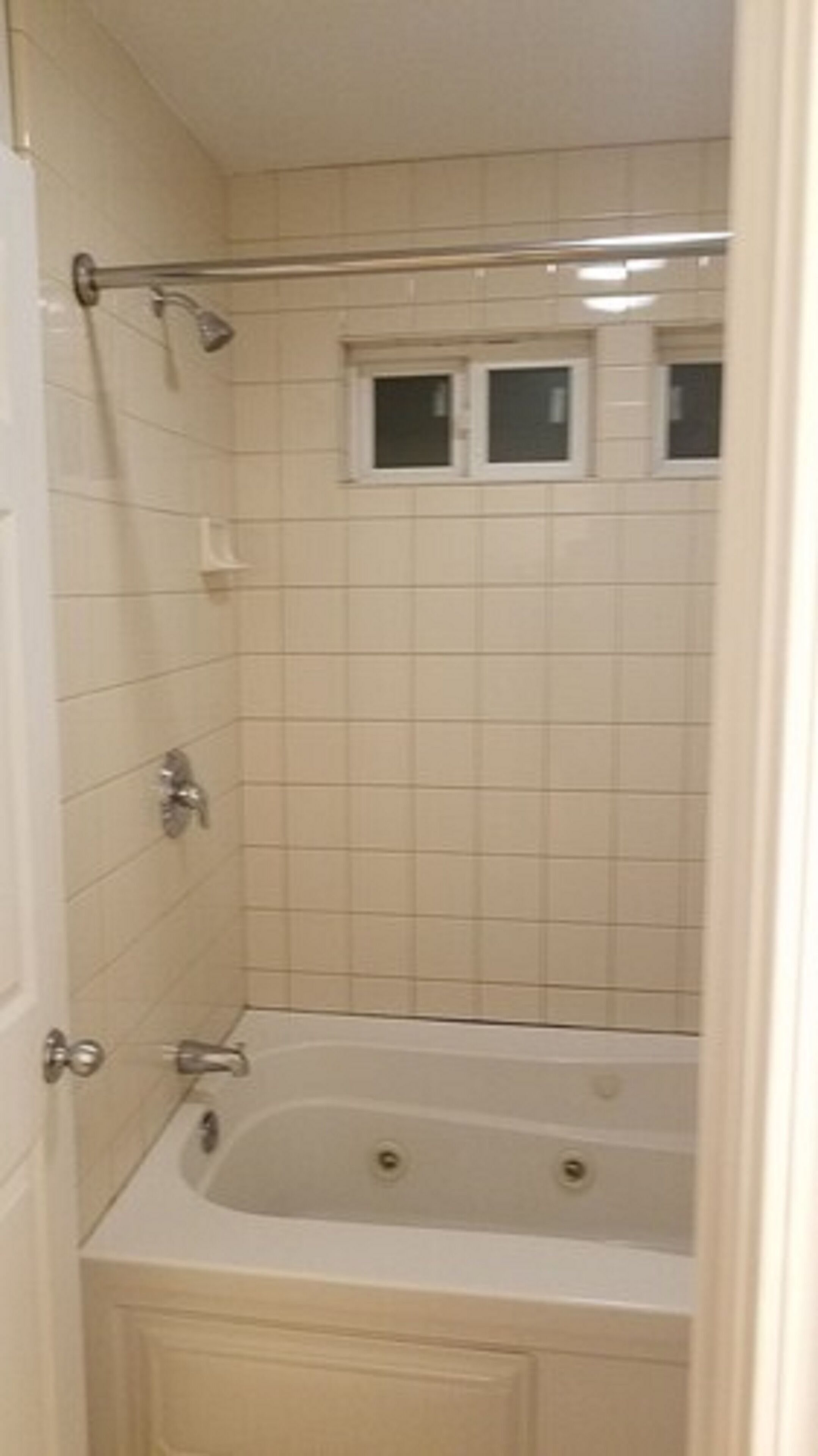 Un baño con bañera, ducha y ventana sobre la bañera.