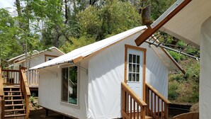 A small, single-story cabin with a wooden staircase leading to a door, surrounded by trees. - Indian Flat RV Park - Tent Cabins & Cottages (El Portal)