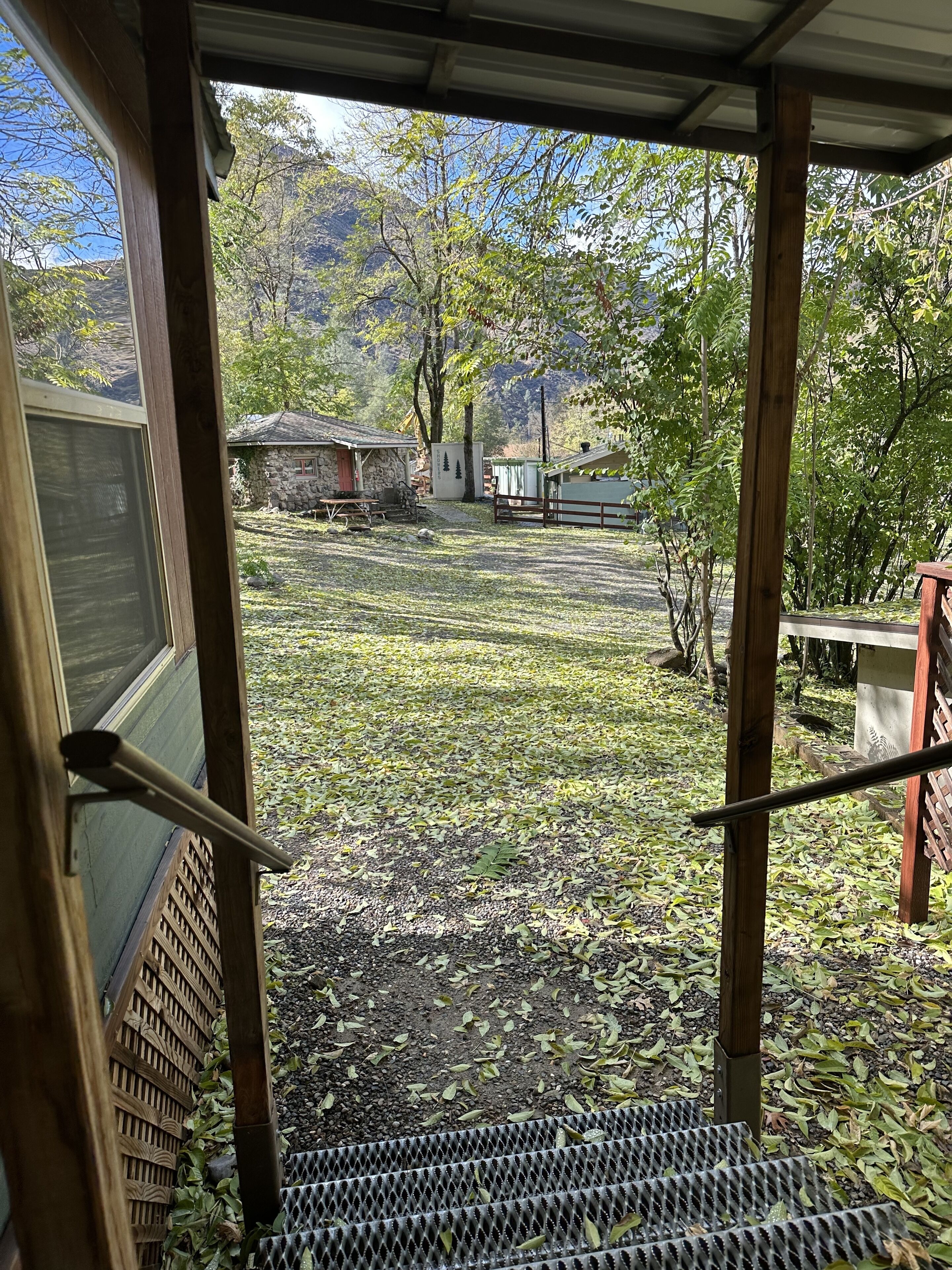 A view from a window overlooking a yard with a wooden fence, a stone building, and a small house.