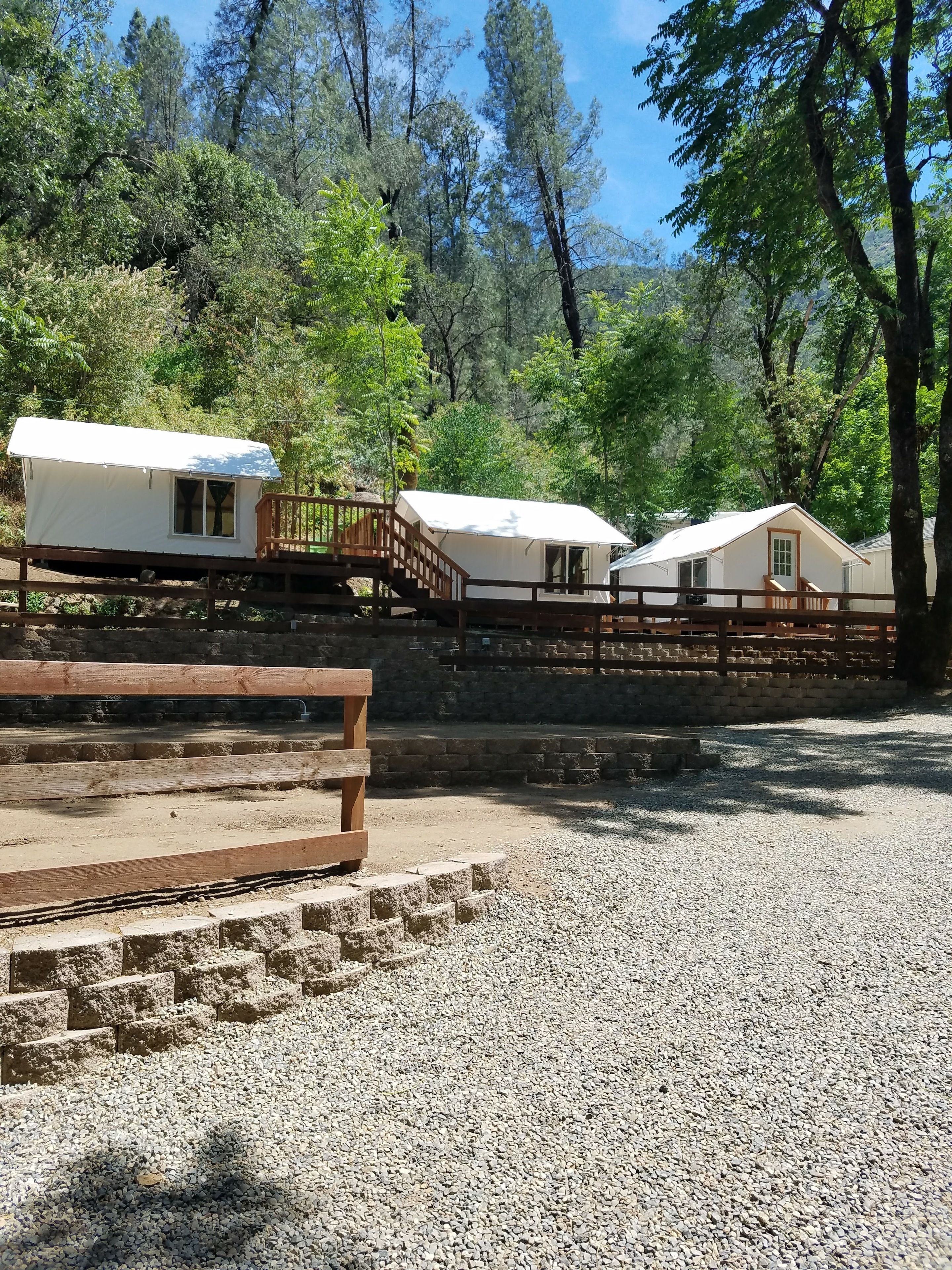 Un camping con varias cabañas blancas, terrazas de madera y un área de grava.