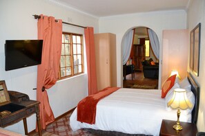 Ein Hotelzimmer mit Bett, Fernseher, Schreibtisch und Lampe.