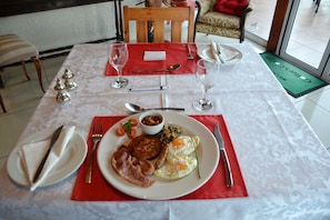 Ein Frühstückstisch gedeckt mit Tellern, Besteck und einer roten Serviette.