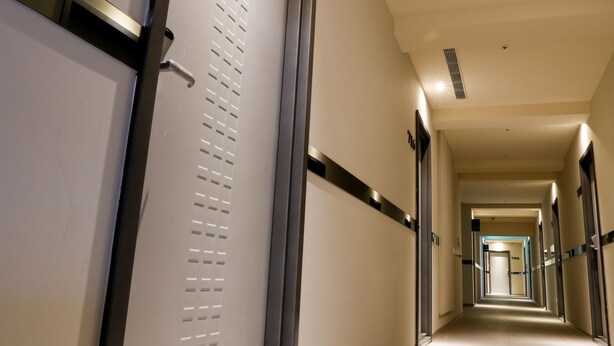 A long, well-lit corridor with doors on both sides, leading to rooms. - Walker Hotel - Zhengyi (New Taipei City)