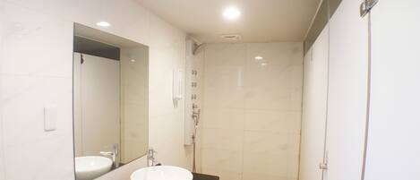 A modern bathroom with a white sink, a large mirror, and a shower area.