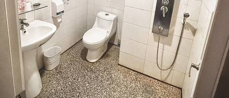 A small, modern bathroom with white tiles, a sink, a toilet, a mirror, and a shower.