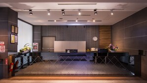 A reception area with a modern design, featuring a reception desk, a clock, and a plant. - Walker Hotel - Zhengyi (New Taipei City)