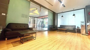 A modern lobby with wooden flooring, two sofas, a small table, and a water dispenser. - Walker Hotel - Zhengyi (New Taipei City)