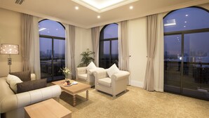 Ein geräumiges Wohnzimmer mit hoher Decke, großen Bogenfenstern und Blick auf die Stadtlandschaft.