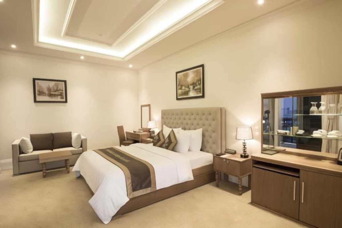 Quarto de hotel com uma cama grande, um sofá, uma escrivaninha e um armário.