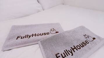 Two towels with the text "FullyHouse" and a cat illustration on a bed.