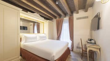 Una habitación de hotel con una cama grande, un escritorio con una silla, un espejo y un televisor en la pared.