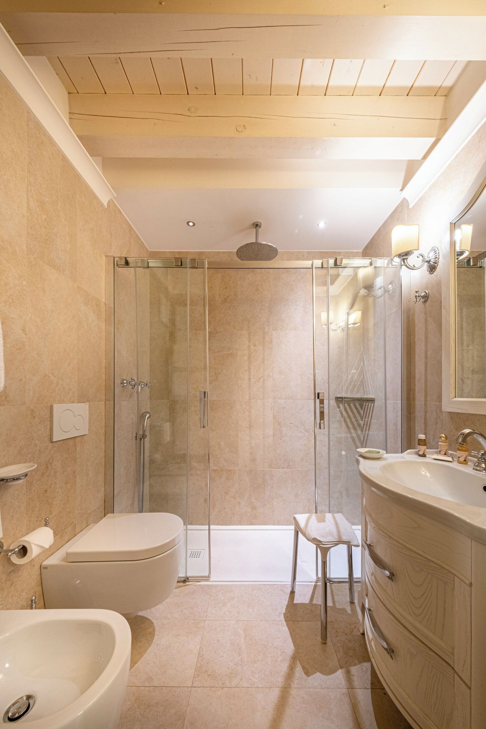 A modern bathroom with a glass-enclosed shower, a white sink, and a vanity with drawers.
