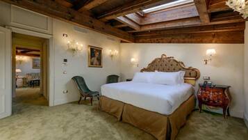 A bedroom with a large bed, a chair, a small table, and a lamp.