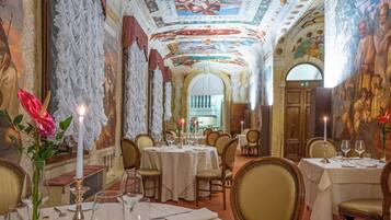Comedor con frescos ornamentales en el techo, candelabros y decoración clásica.