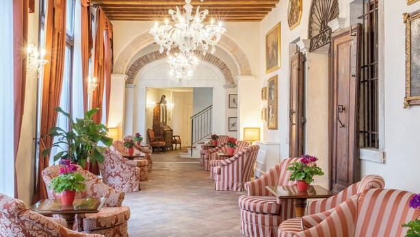 A spacious lobby with striped armchairs, a grand chandelier, and a piano. - Hotel Villa Barbarich (Mestre)