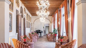A grand hallway with striped armchairs, a grand piano, and a chandelier. - Hotel Villa Barbarich (Mestre)