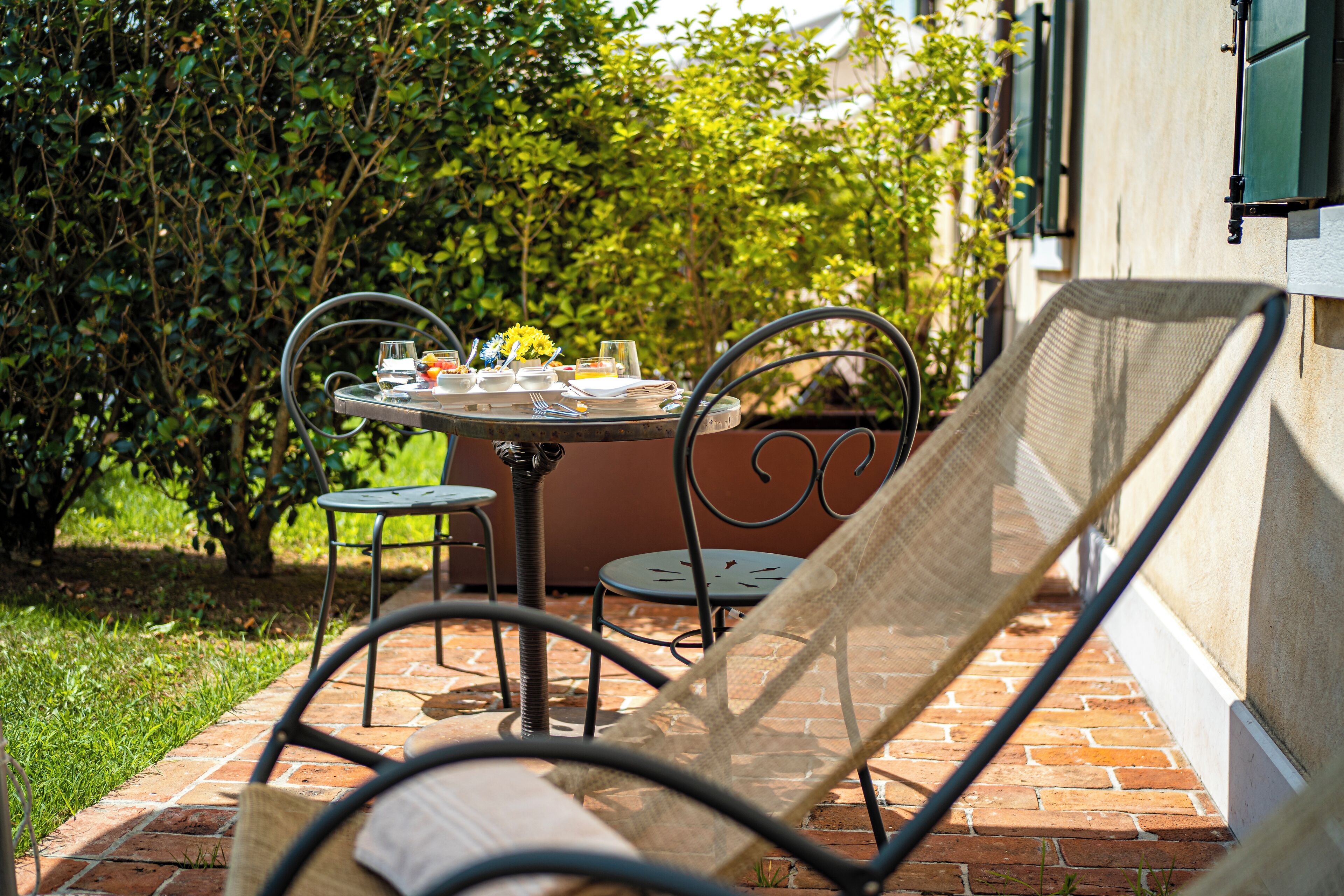 Un patio al aire libre con una mesa redonda lista para comer, rodeada de sillas de metal.