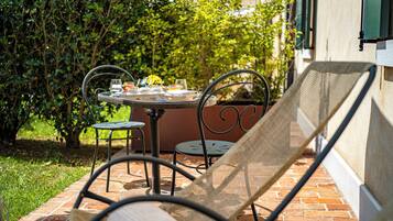 Un patio al aire libre con una mesa redonda lista para comer, rodeada de sillas de metal.