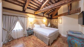 Un dormitorio con una cama grande, vigas de madera, una mesita de noche, un aparador y una ventana con cortinas.