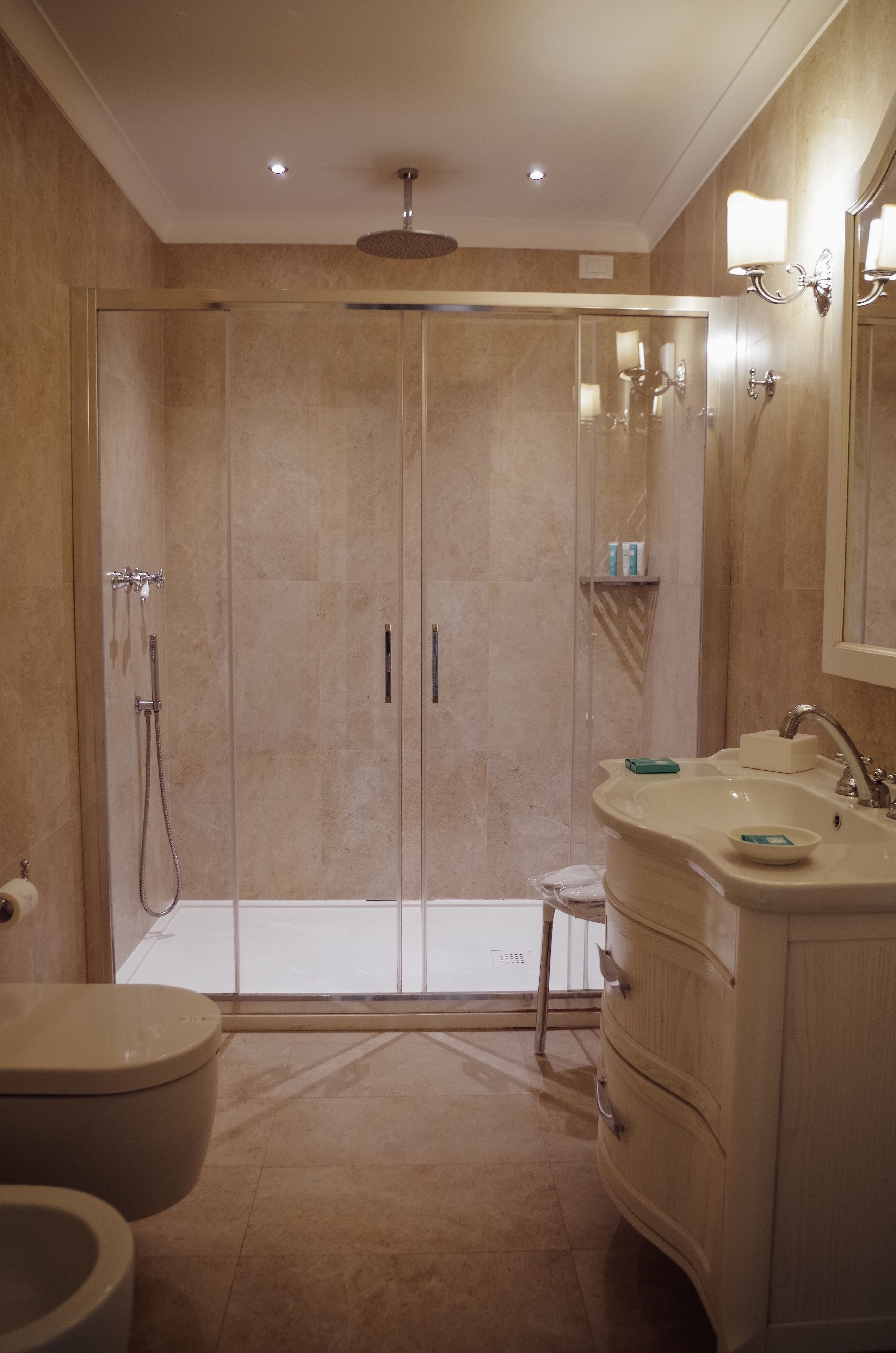Un bagno moderno con doccia a filo pavimento, un water e un mobile lavabo con lavandino e specchio.