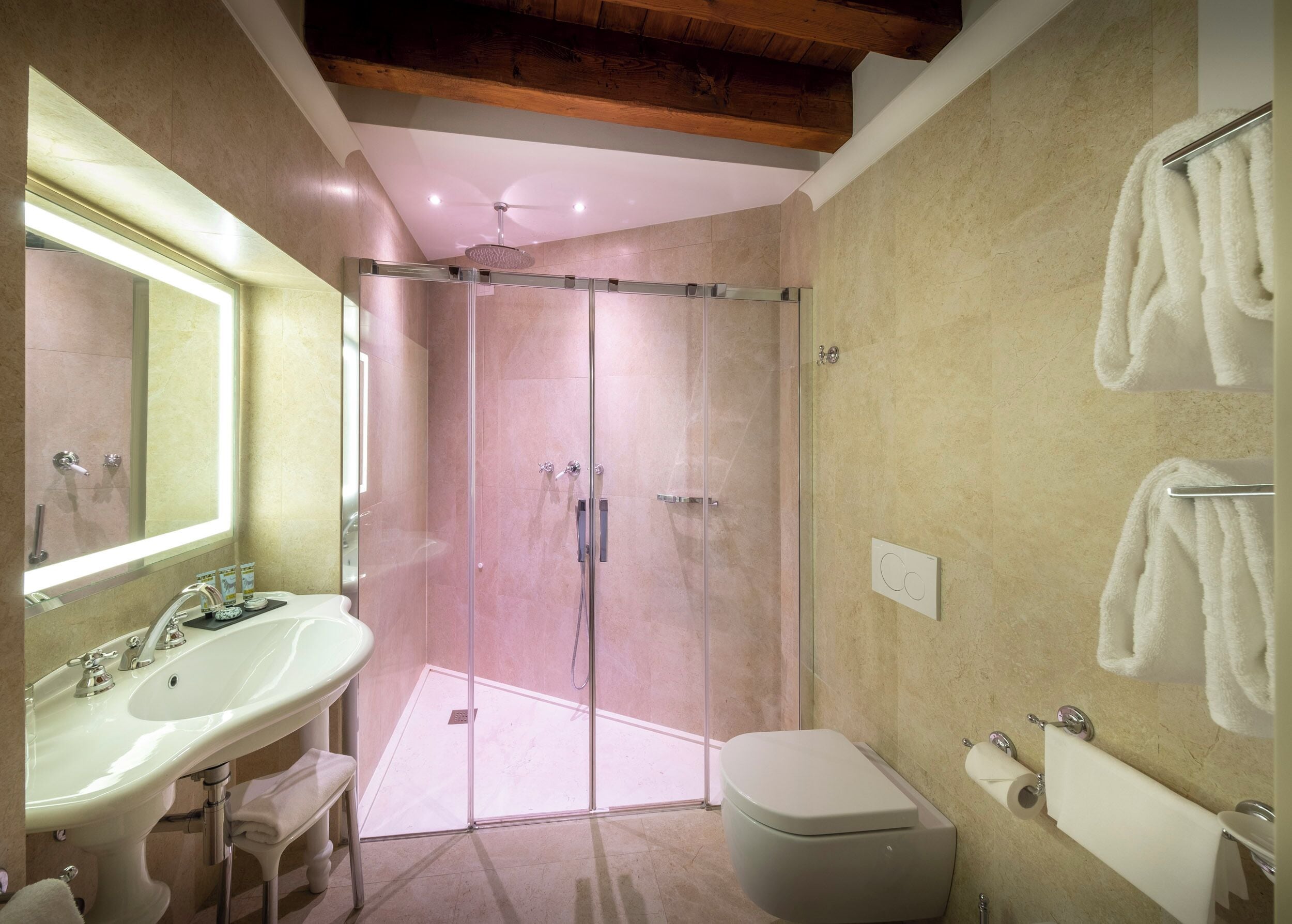 Ein modernes Badezimmer mit einer gläsernen Duschkabine, einem Waschbecken mit Spiegel und einer Toilette.