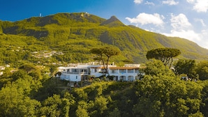 Una villa en una ladera con vistas a una montaña y un faro a lo lejos.