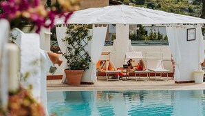 Un área de piscina con sillones de descanso y una planta en maceta.