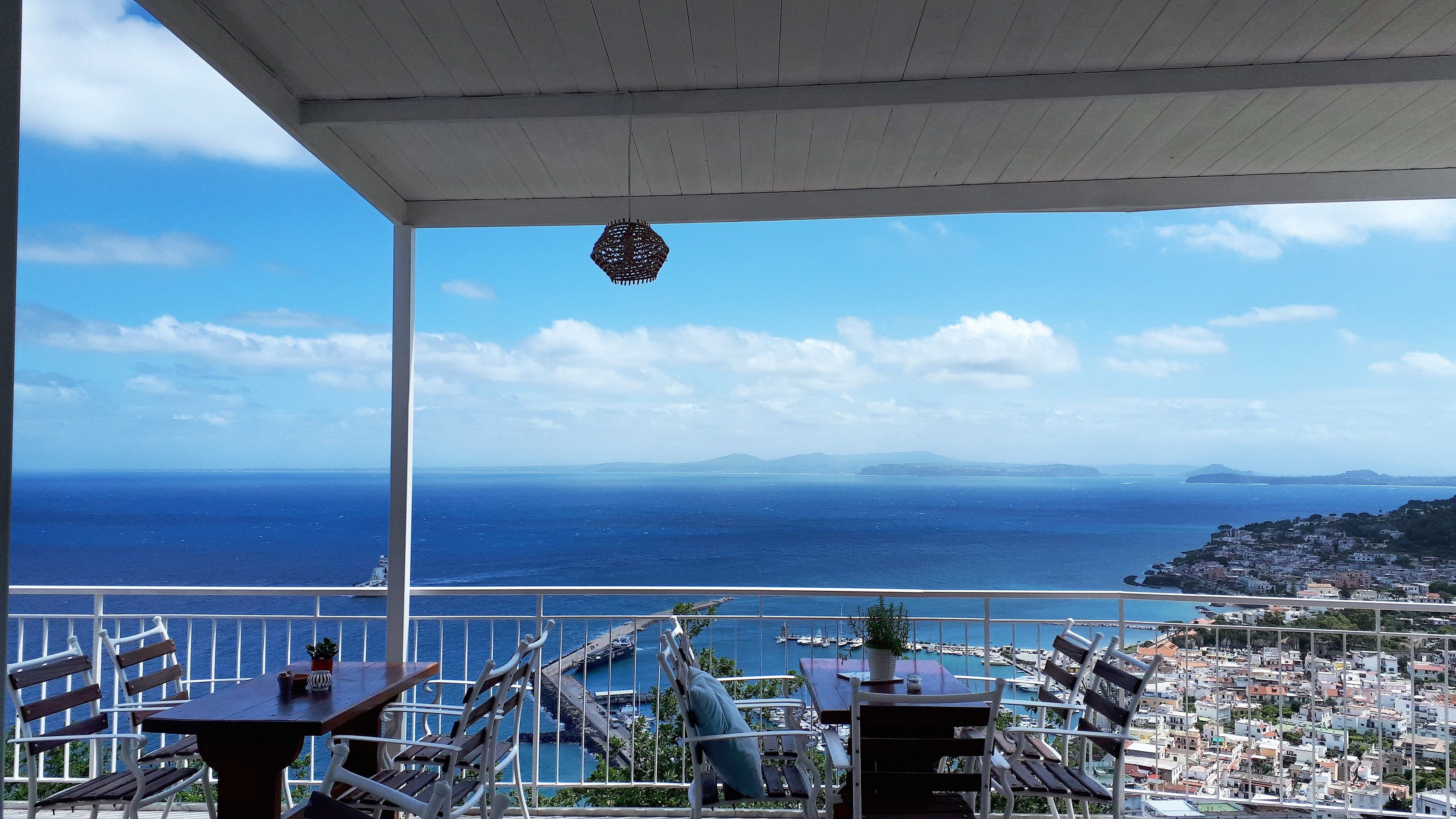 A terrace with a view of the sea and a coastal town.
